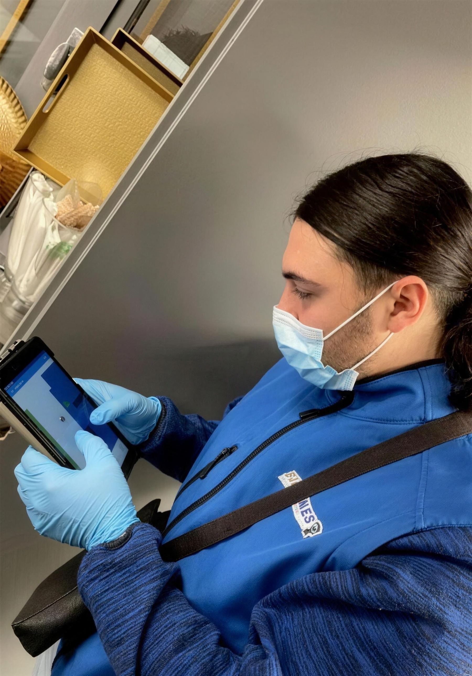 Technicien de Nuisibles Assistance, masque et gants, qui renseigne son diagnostic sur une tablette